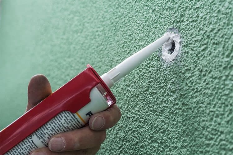 Acryl wird mit der Spitze einer roten Kartusche in die ausgefräste Vertiefung eingebracht.